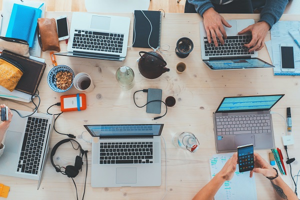 Picture of a group of people working together on laptops and mobile devices.